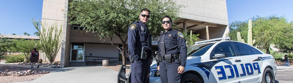 Two PCC police officers pose in front of their squad car