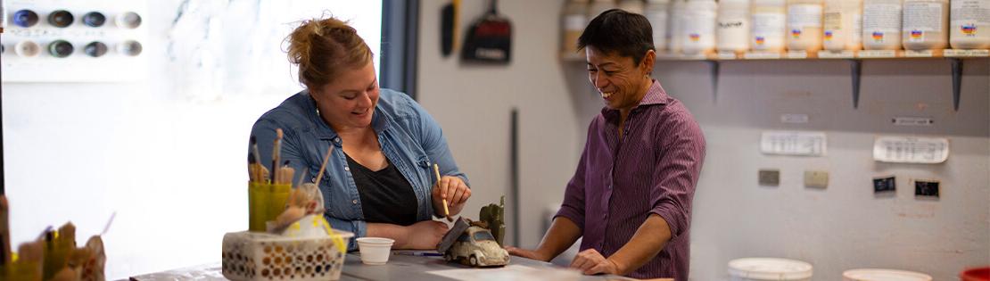 Two Pima students work on some pottery