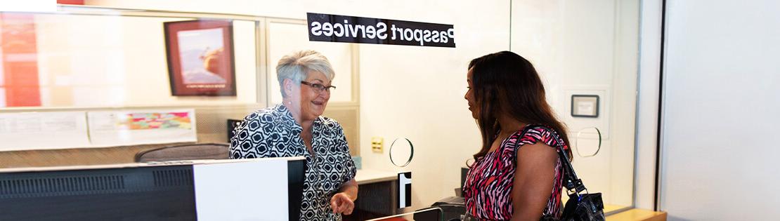 A woman speaks with the Passport Services Front Desk Assistant at Pima's East Campus